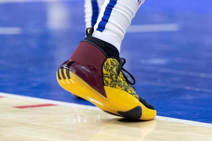 View of maroon and gold adidas Harden shoes.